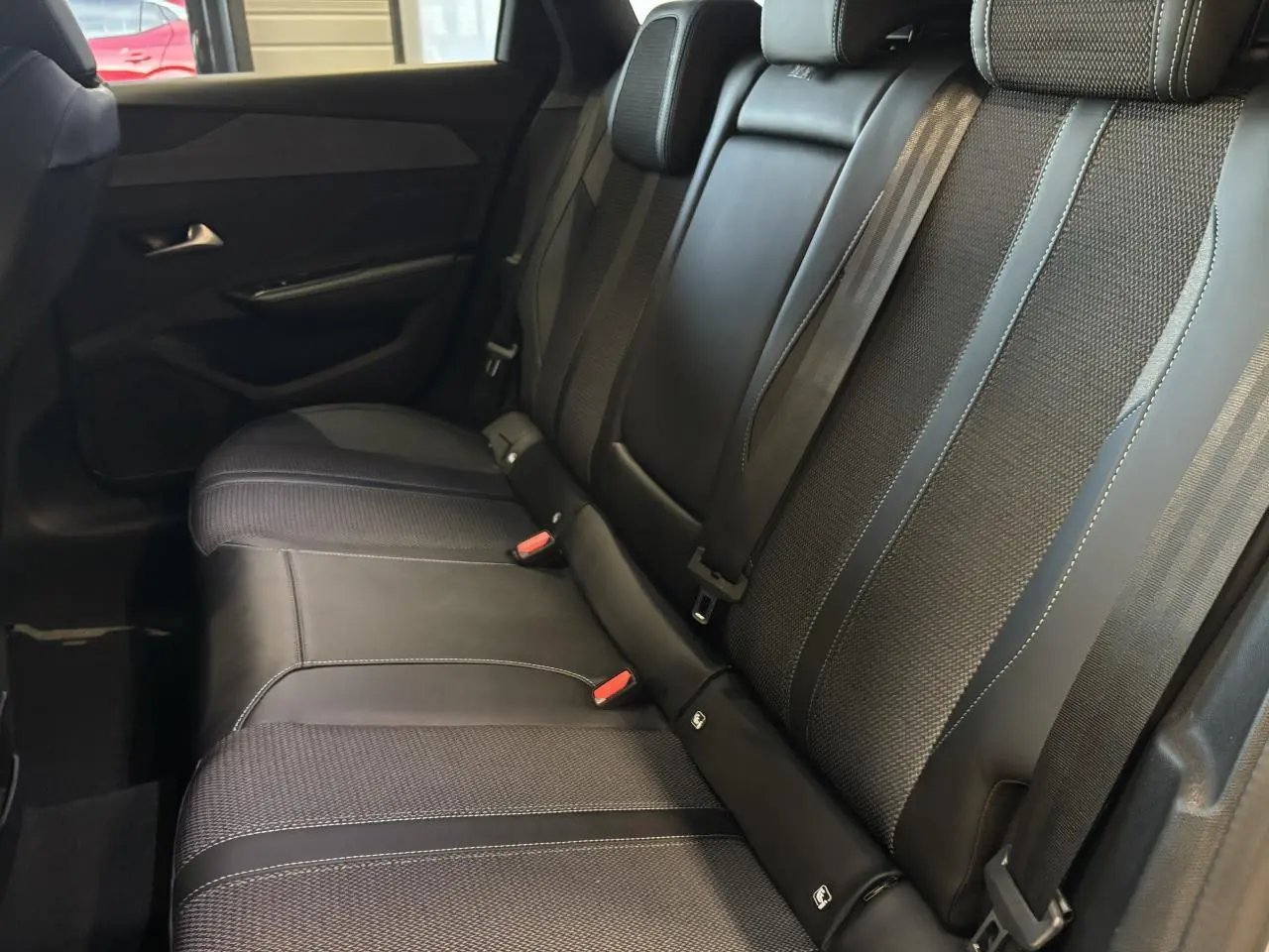 Vue latérale intérieure montrant la banquette arrière en sellerie tri matières noire avec surpiqûres bleues du Peugeot 308 SW 2024.