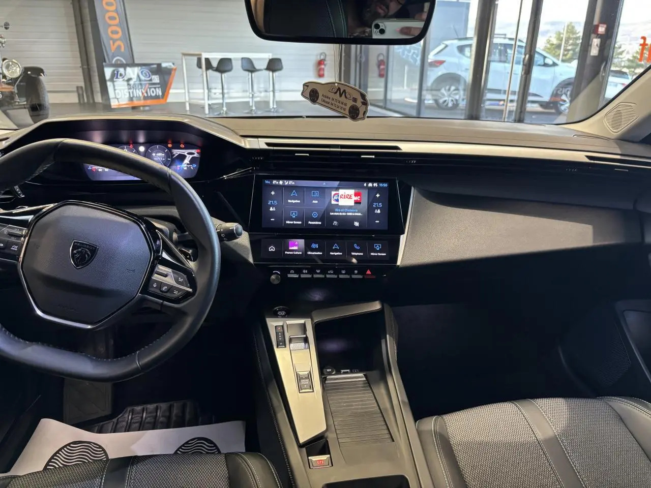 Vue intérieure avant de la Peugeot 308 SW 2024, tableau de bord moderne avec écran tactile central et volant cuir noir.