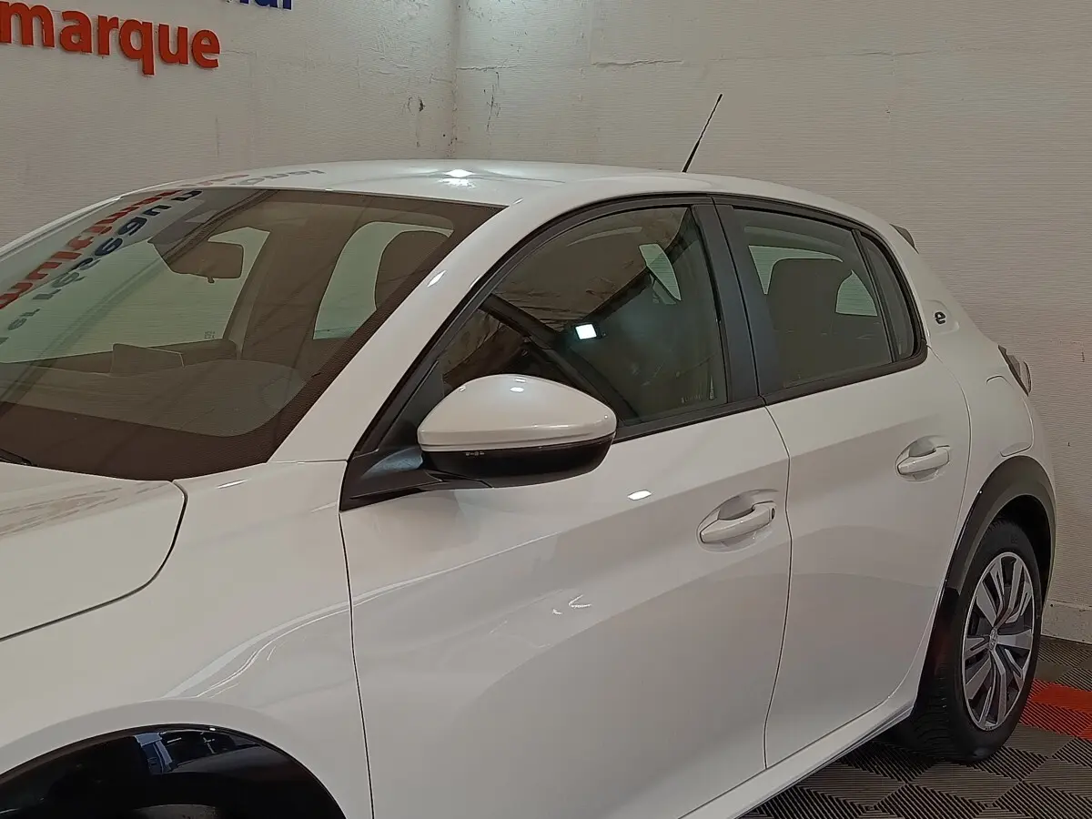 Vue côté gauche d'une Peugeot 208 électrique Active Business blanche, avec rétroviseur et poignées assortis.
