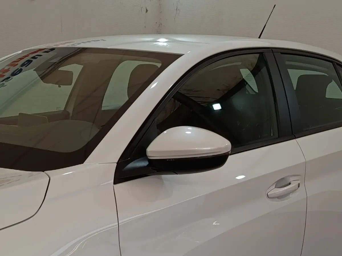 Vue latérale côté gauche d'une Peugeot 208 Electrique Active Business blanche, avec rétroviseur assorti.