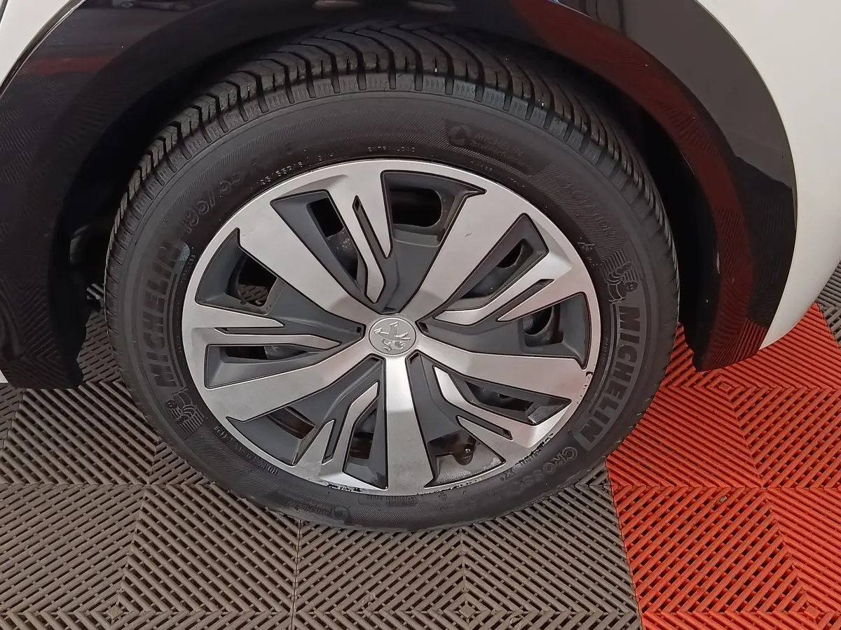 Gros plan sur la roue avant droite de la Peugeot 208 Electrique Active Business blanche, jante alliage moderne.