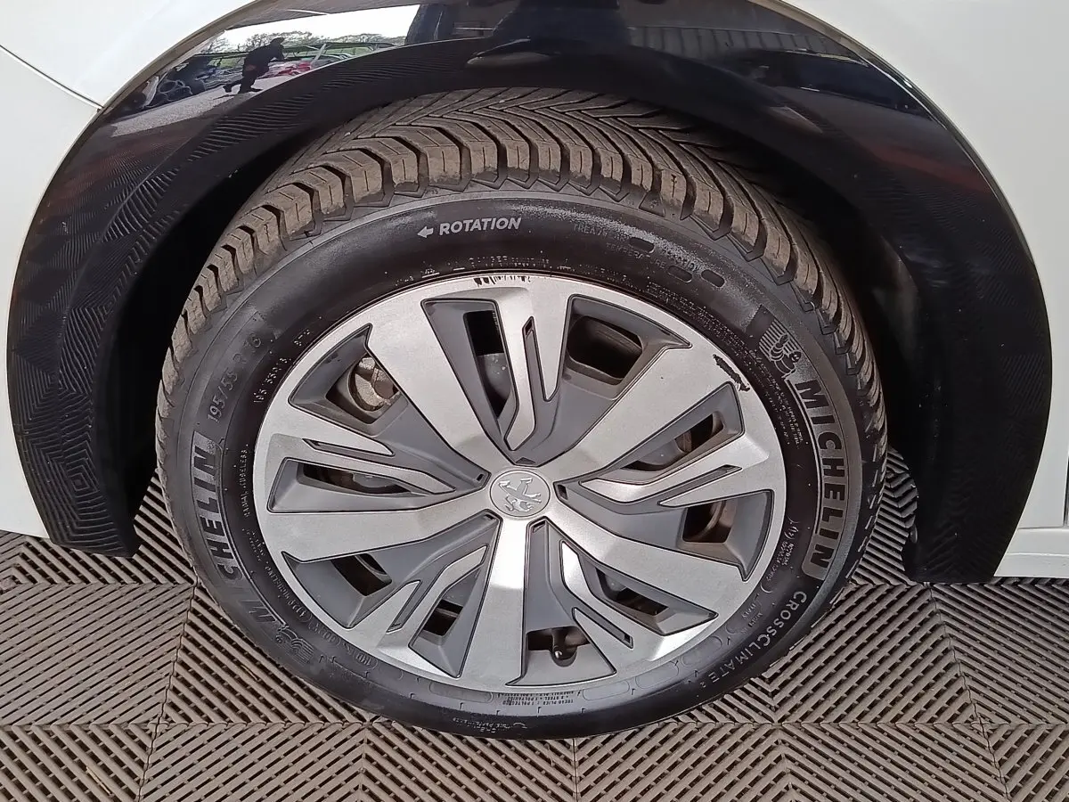 Gros plan sur la roue avant droite de la Peugeot 208 électrique blanche, avec jante en alliage et pneu Michelin.