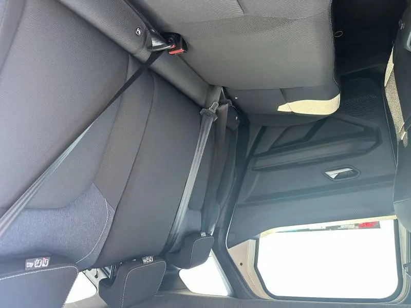 Vue intérieure arrière du Dacia Duster blanc 2025, montrant la banquette noire avec ceintures de sécurité et appuie-têtes.