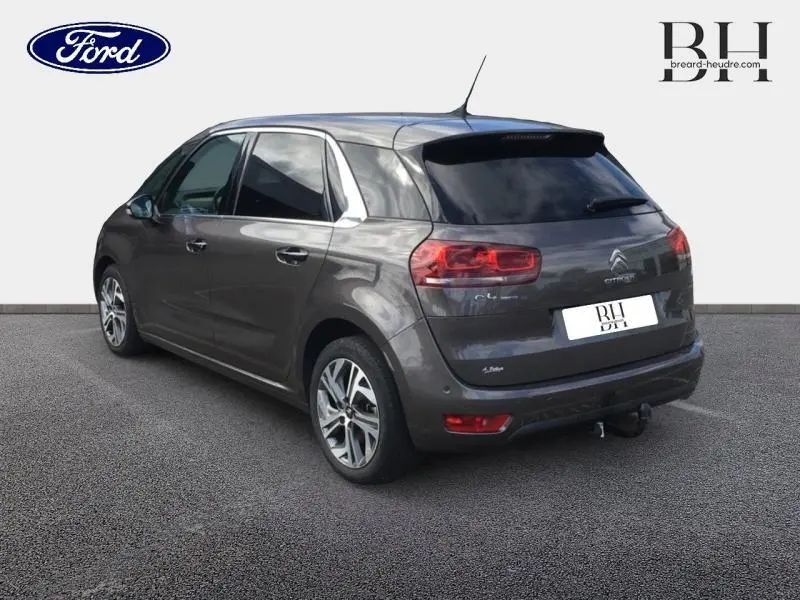 Vue 3/4 arrière droite d'une Citroën C4 Picasso gris Shark avec jantes alu et vitres surteintées.