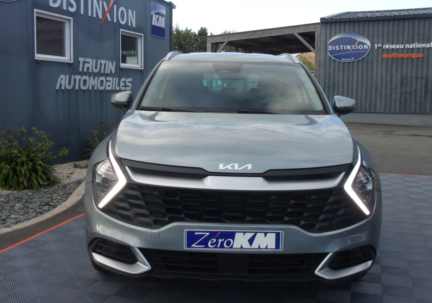 Vue frontale d'un KIA Sportage gris perle avec feux LED en forme de flèche et calandre noire distinctive.