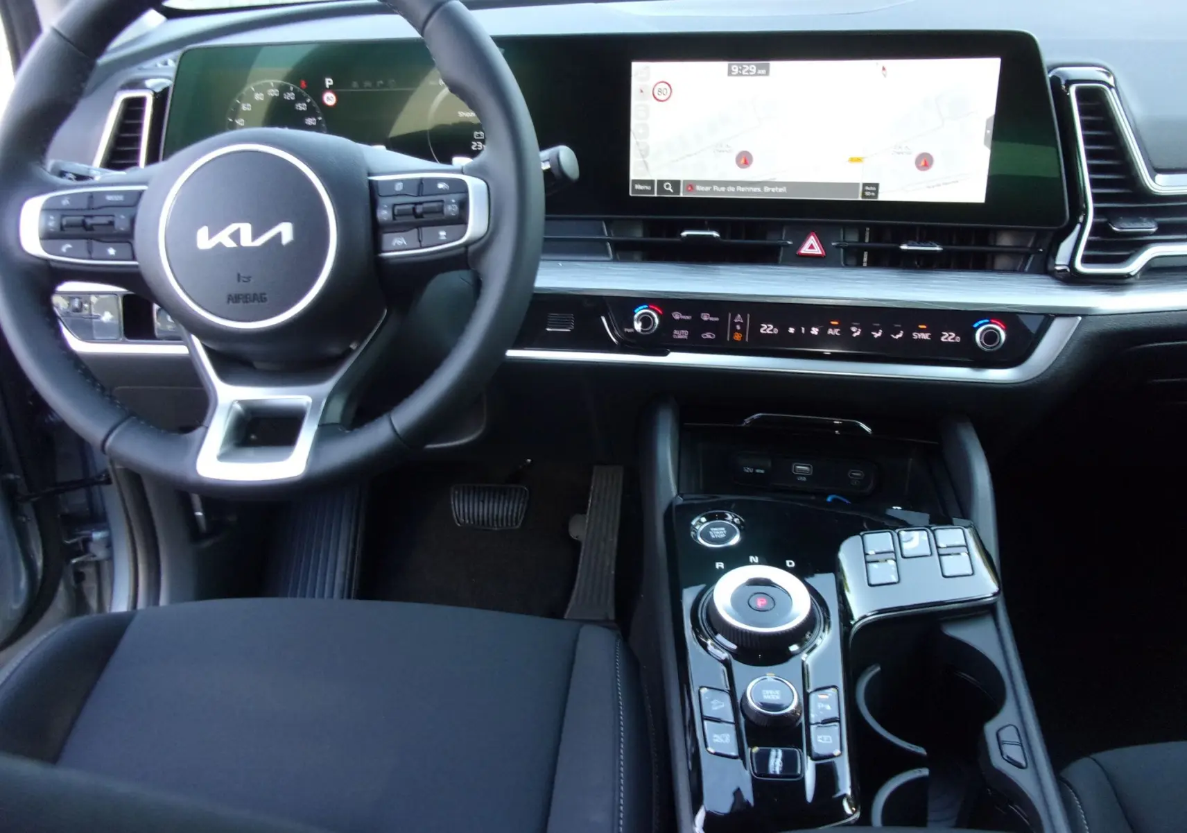 Intérieur du Kia Sportage 2025 gris perle, vue centrée sur le volant multifonction et l'écran tactile GPS 12,3 pouces.