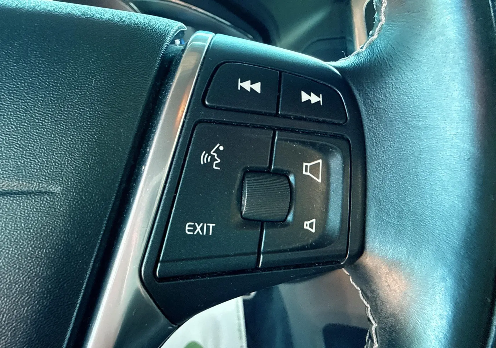 Gros plan sur les commandes noires du volant cuir du Volvo XC60 gris, version D4 Momentum 2016.