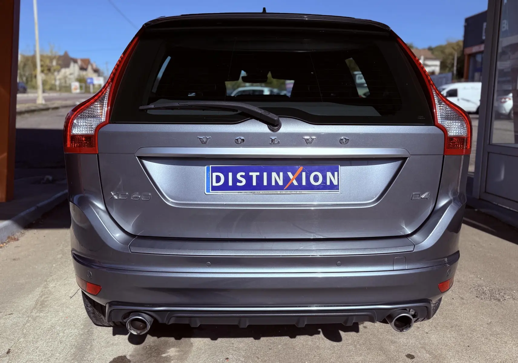 Vue arrière d'un Volvo XC60 D4 gris 2016 avec double sortie d'échappement et logo Distinxion sur la plaque.