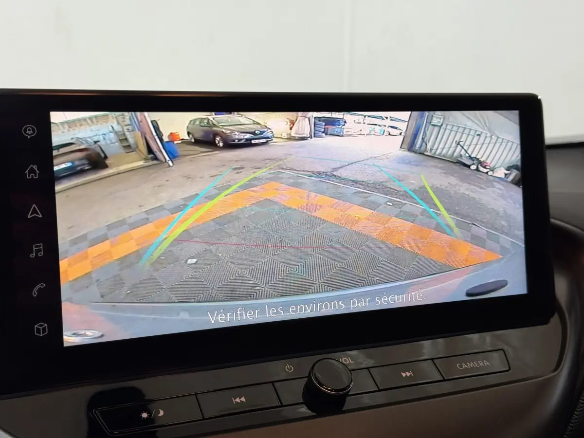 Écran tactile intérieur montrant la caméra de recul du Nissan Juke gris clair, avec lignes de guidage colorées.