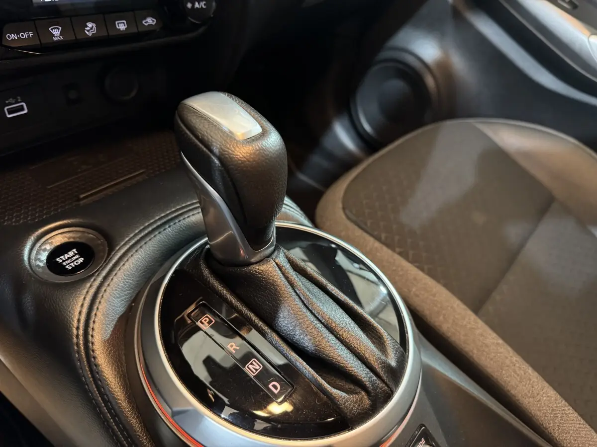 Gros plan sur le levier de vitesse automatique noir et argent du Nissan Juke gris clair, avec bouton démarrage visible.