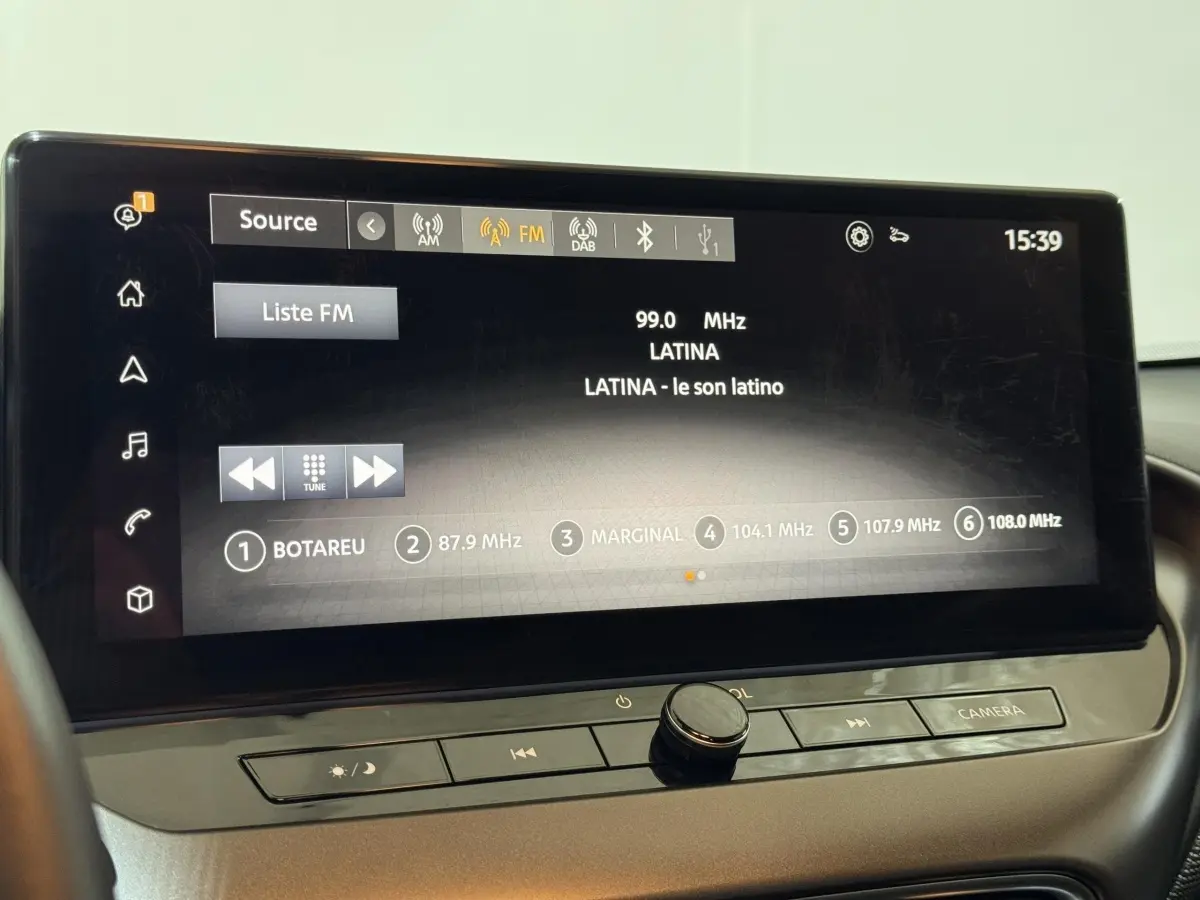 Écran tactile central affichant la radio FM dans l'habitacle du Nissan Juke gris clair, vue de face rapprochée.
