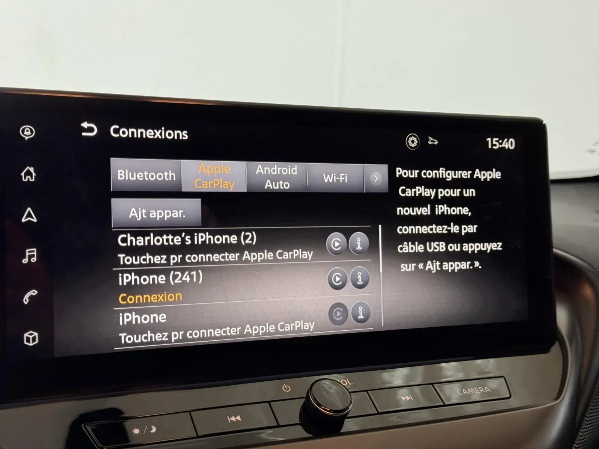 Gros plan sur l’écran tactile central du Nissan Juke 2025 gris clair affichant les options de connexion Apple CarPlay et Bluetooth.