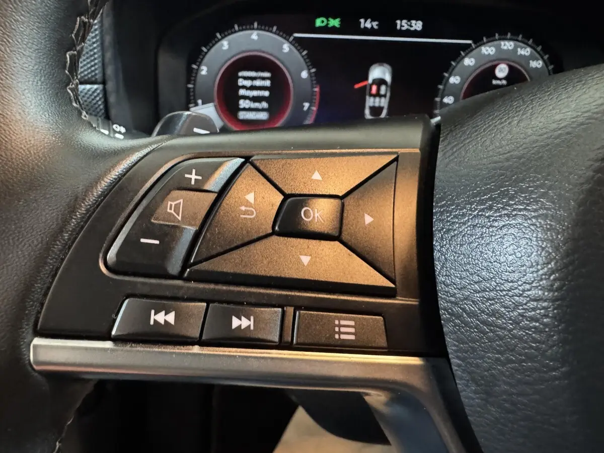 Gros plan sur les commandes multifonctions côté gauche du volant cuir du Nissan Juke gris clair 2025.