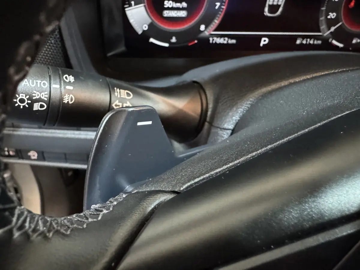 Gros plan sur la palette de changement de vitesse côté gauche du volant cuir noir du Nissan Juke gris clair 2025.