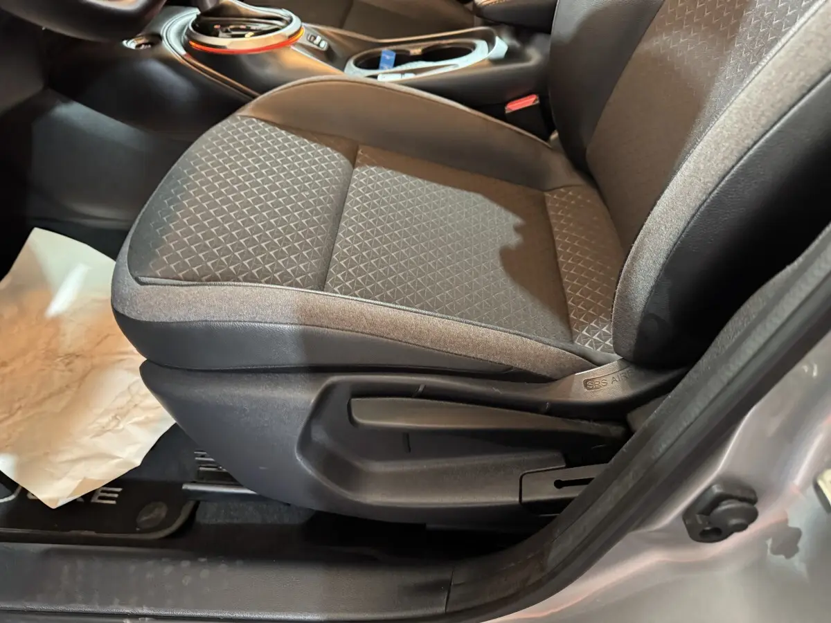 Gros plan sur le siège avant droit gris clair du Nissan Juke 2025, avec réglage manuel visible et tissu texturé.