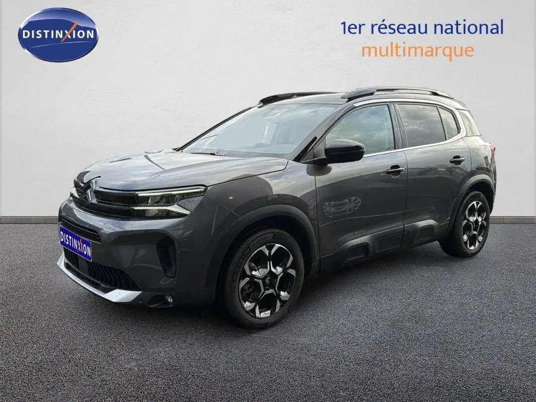 Vue de profil côté gauche du Citroën C5 Aircross Hybrid gris platinium avec jantes bi-ton et barres de toit.