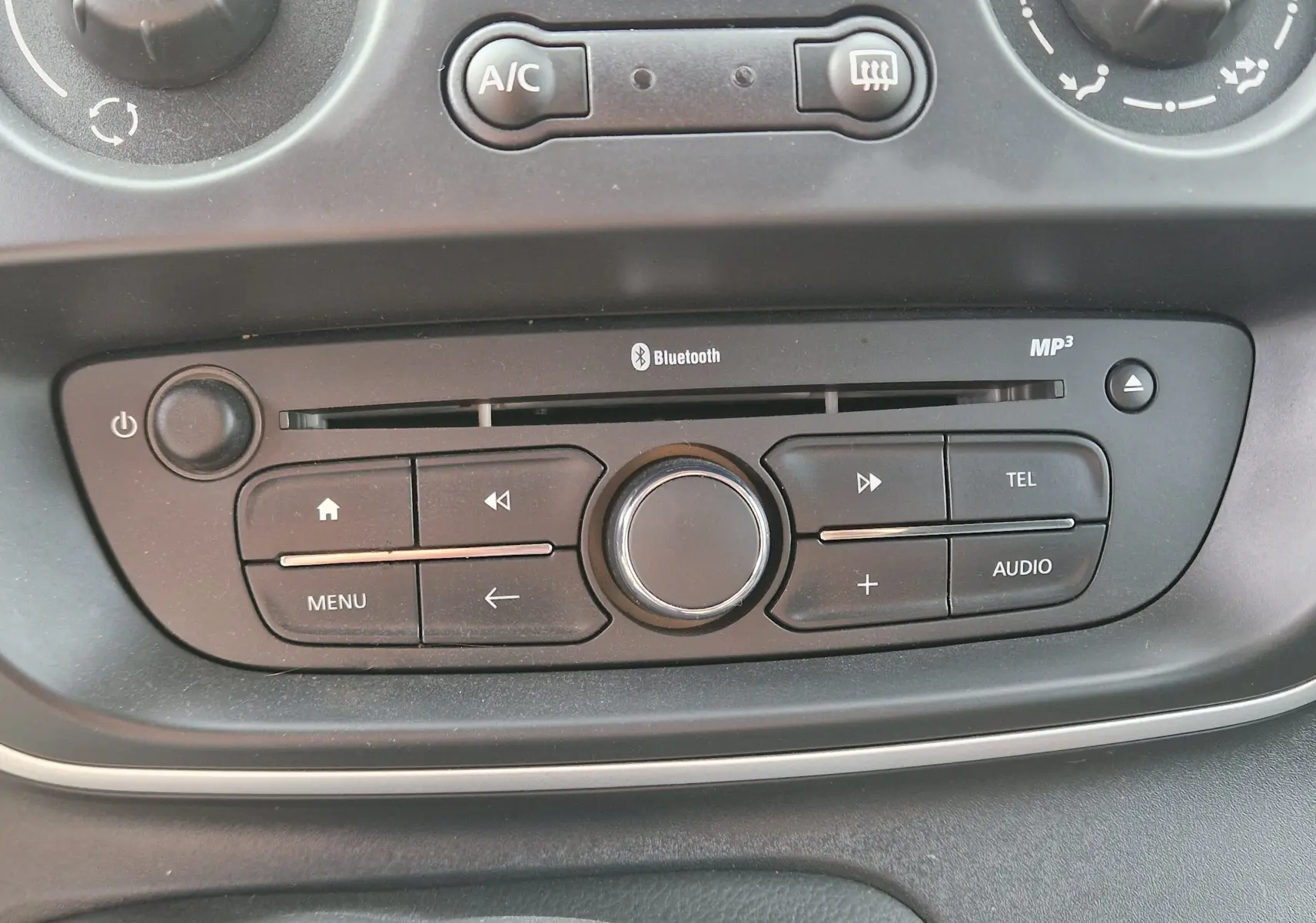 Vue rapprochée du panneau de commande audio noir avec boutons Bluetooth et MP3 du Renault Kangoo blanc 2021.