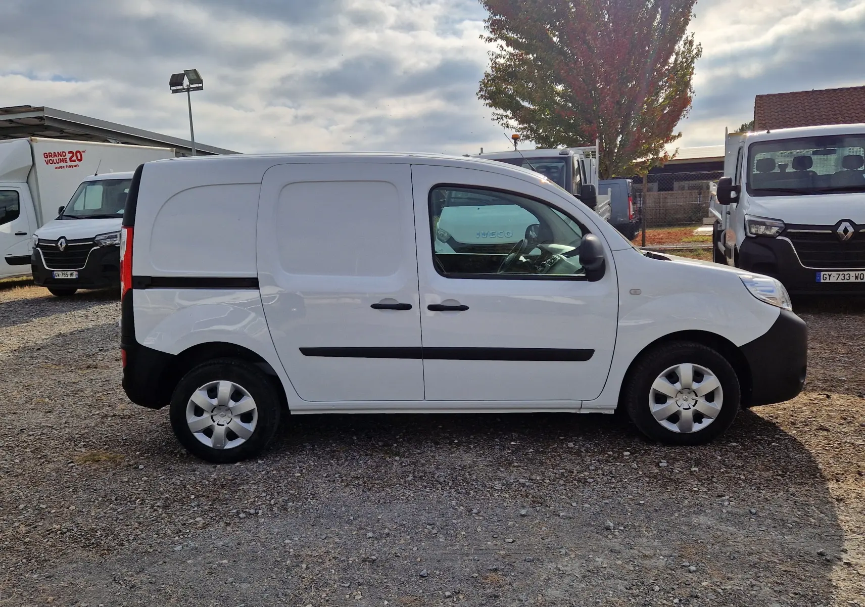 Profil côté droit d’un Renault Kangoo blanc 2021 utilitaire avec protections noires et jantes argentées sur un parking.