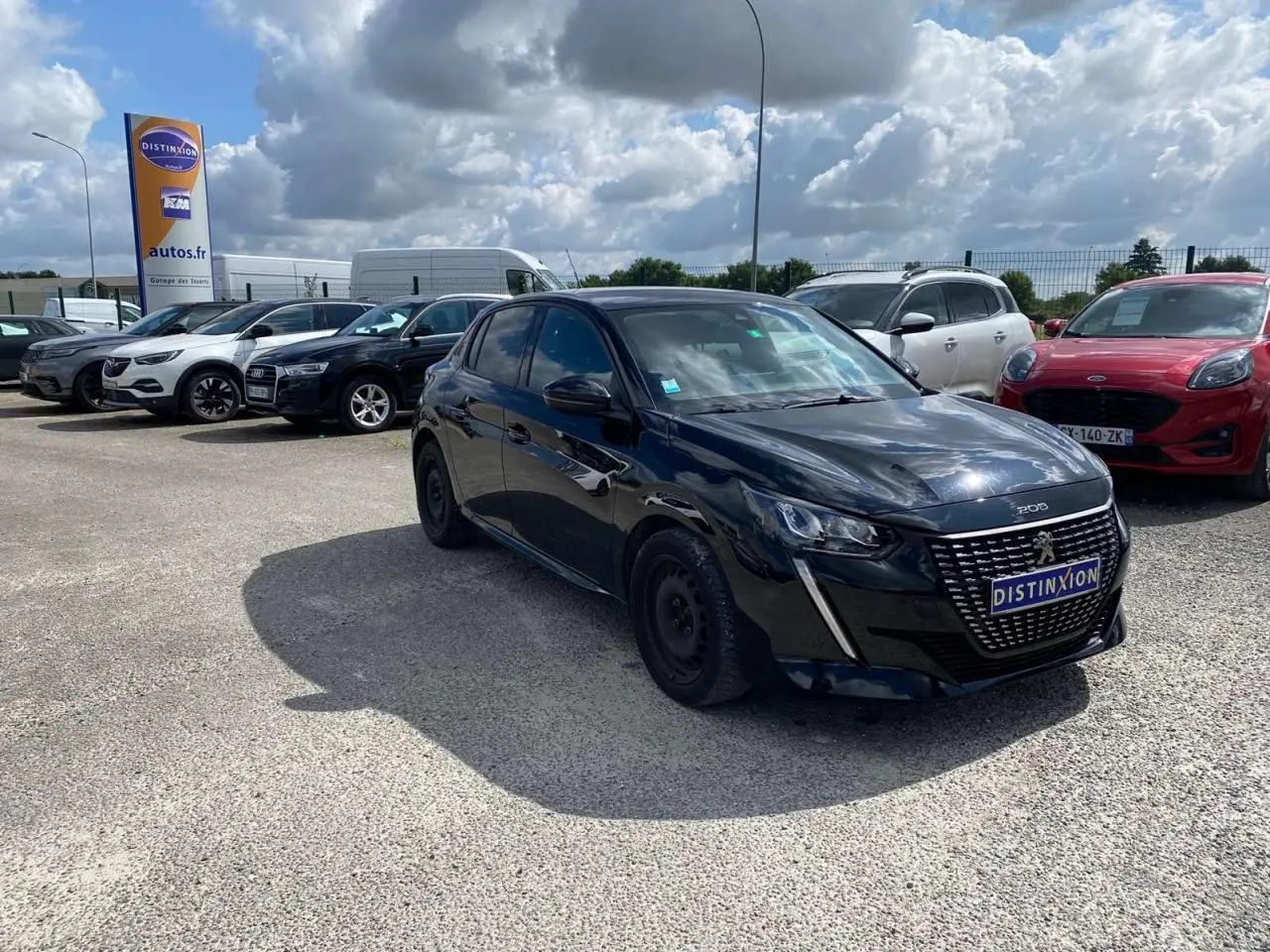 Peugeot 208 noire vue en 3/4 avant droit sur parking, avec calandre distinctive et jantes acier noires.