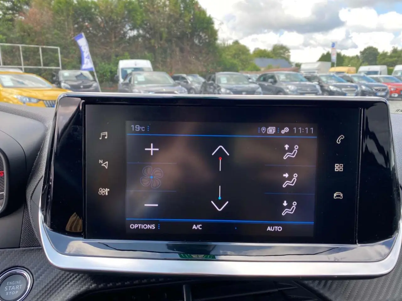 Écran tactile 7 pouces du tableau de bord de la Peugeot 208 noire, avec commandes climatisation visibles.