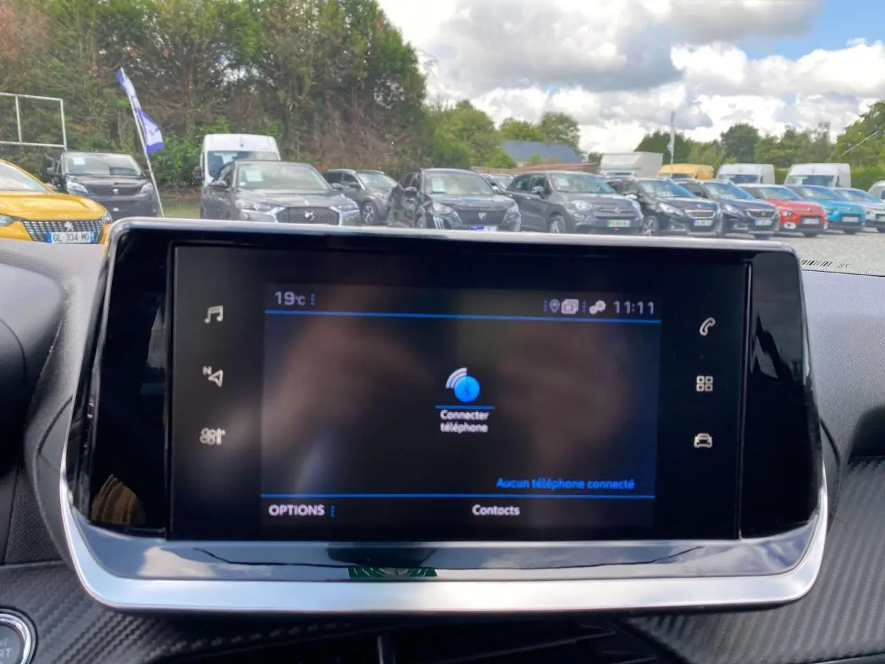 Écran tactile 7 pouces du tableau de bord d'une Peugeot 208 noire, affichant la connexion téléphone.