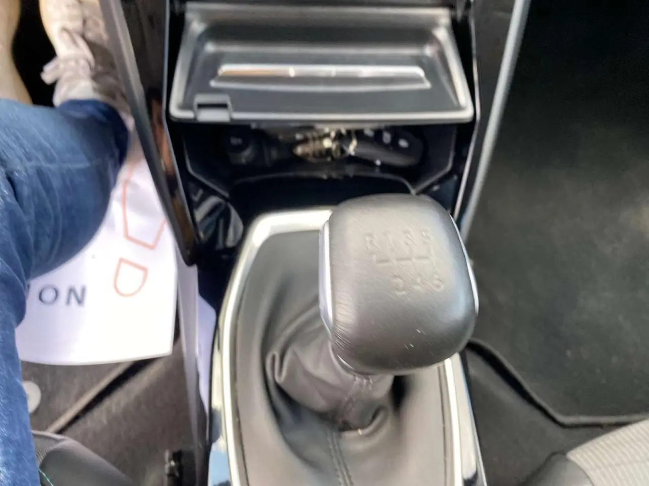 Gros plan sur le levier de vitesses manuel de la Peugeot 208 noire, avec console centrale brillante visible.