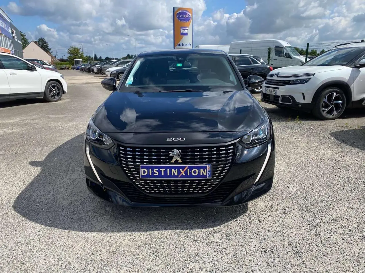 Peugeot 208 noire vue de face, avec calandre distinctive et phares LED en forme de griffes.