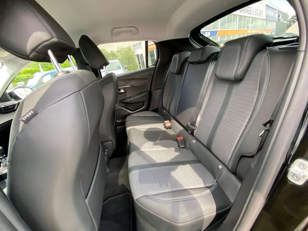 Vue intérieure côté droit des sièges arrière en tissu gris et noir de la Peugeot 208 noire de 2021.