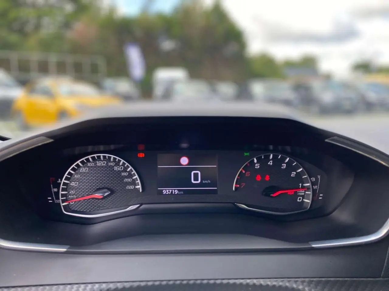 Vue rapprochée du tableau de bord numérique de la Peugeot 208 noire, affichant le compteur et le compte-tours.