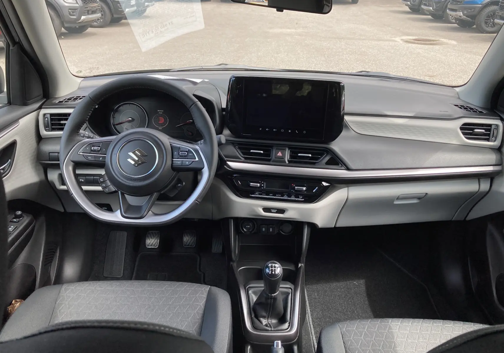 Intérieur de la Suzuki Swift 1.2 Dualjet Hybrid Allgrip Pack 2025, vue frontale sur le tableau de bord et volant multifonctions cuir.