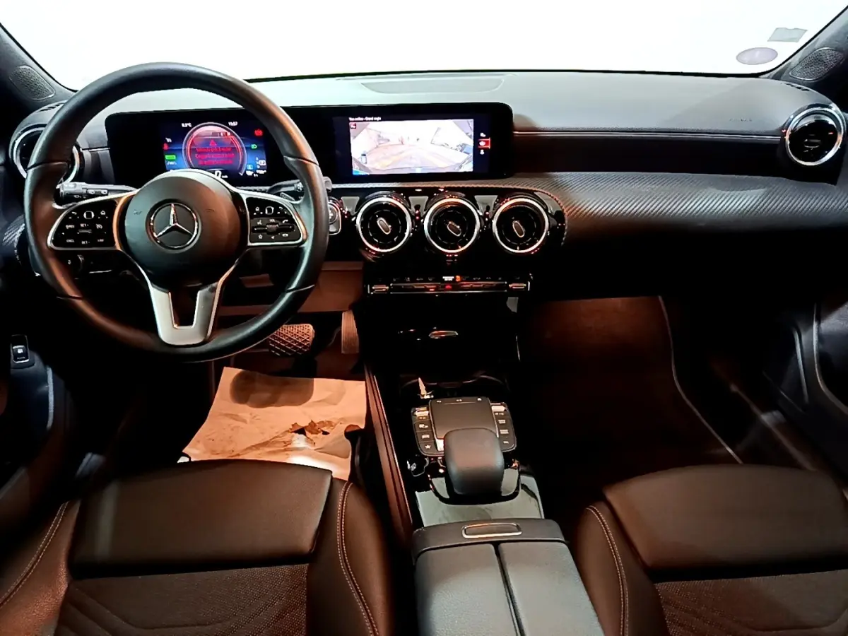 Vue intérieure avant de la Mercedes Classe A 250 e Business Line 2020, tableau de bord noir avec écran tactile et volant cuir multifonctions.