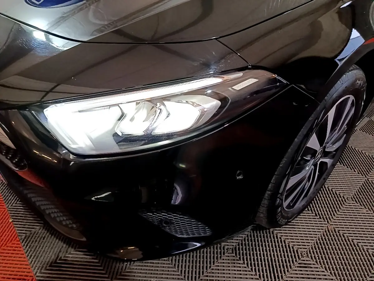 Gros plan sur l'avant droit noir d'une Mercedes Classe A 250 e avec phare LED et jante alliage visible.