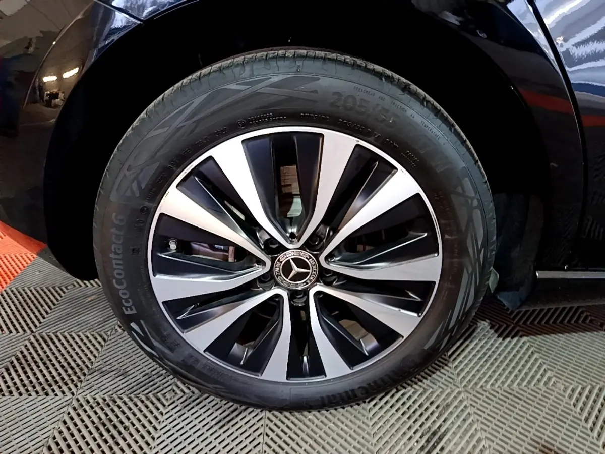 Gros plan sur la roue avant droite d'une Mercedes Classe A 250 e Business Line noire avec jante alliage bicolore.