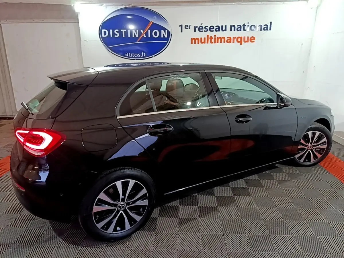 Vue 3/4 arrière côté gauche d'une Mercedes Classe A 250 e Business Line noire avec feux arrière LED allumés.