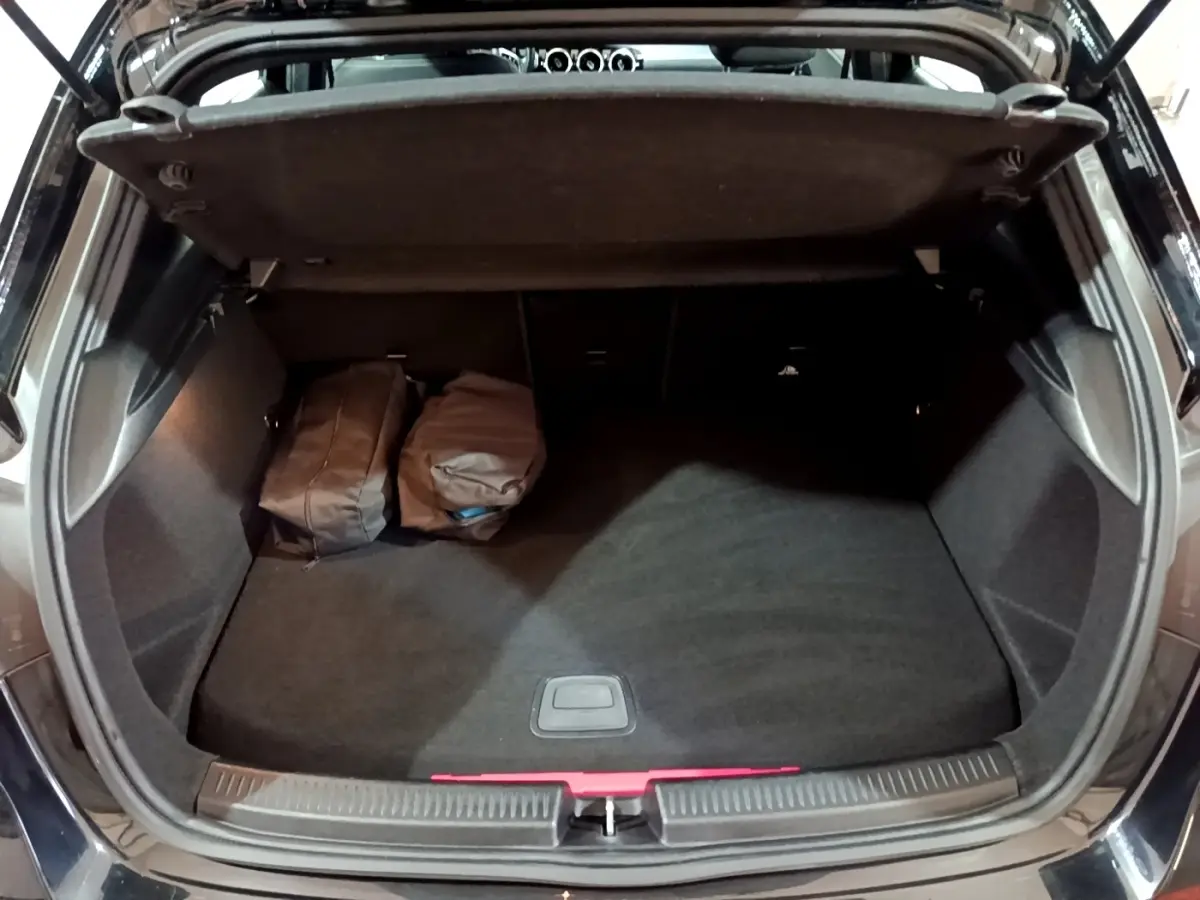 Coffre ouvert vu de l'arrière d'une Mercedes Classe A 250 e Business Line noire avec deux sacs à l'intérieur.
