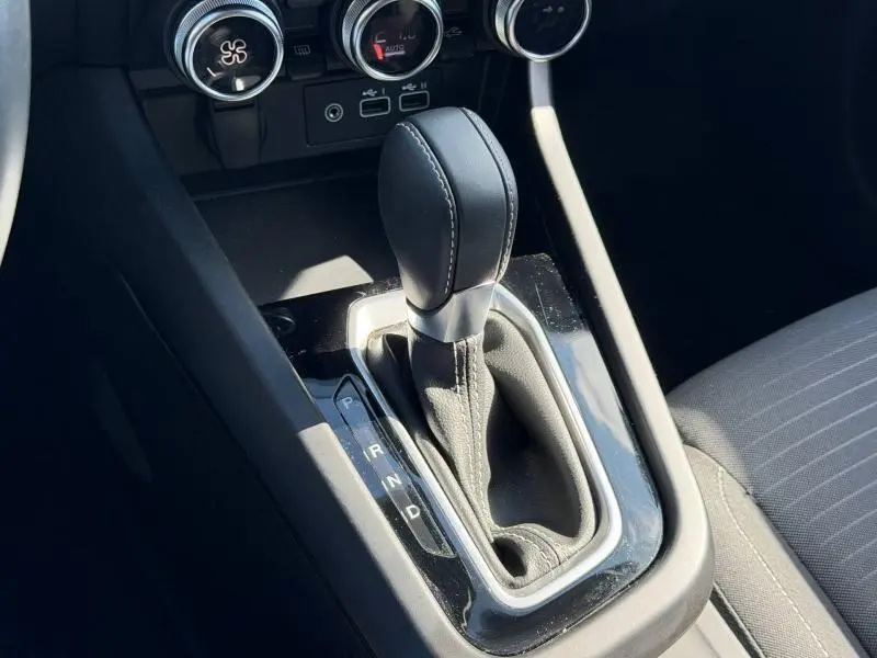 Gros plan sur le levier de vitesses automatique noir du Renault Arkana gris métallique, avec commandes de climatisation en arrière-plan.