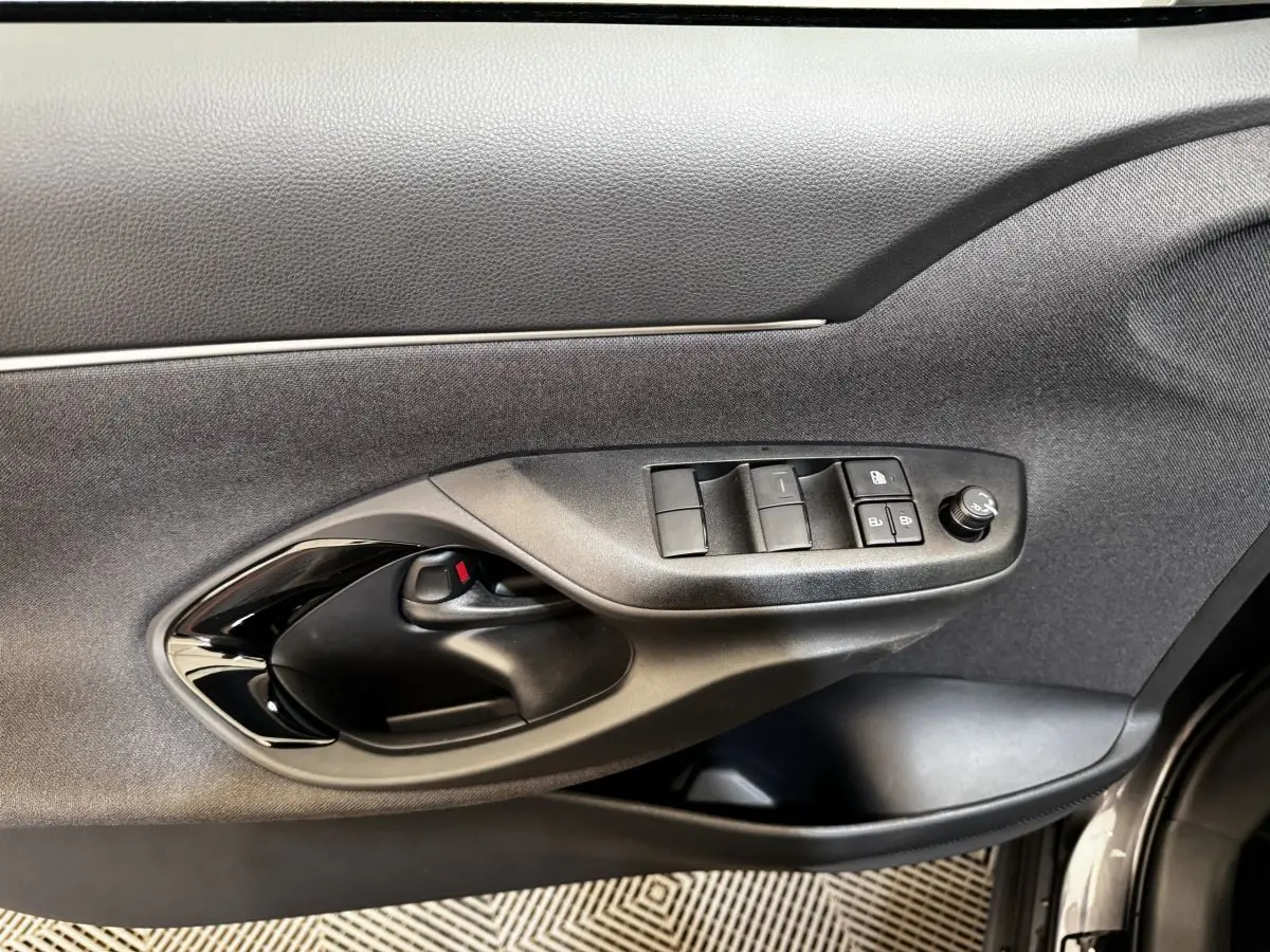 Vue rapprochée de la porte avant gauche grise du Toyota Yaris Cross 2026, avec commandes électriques et poignée noire.