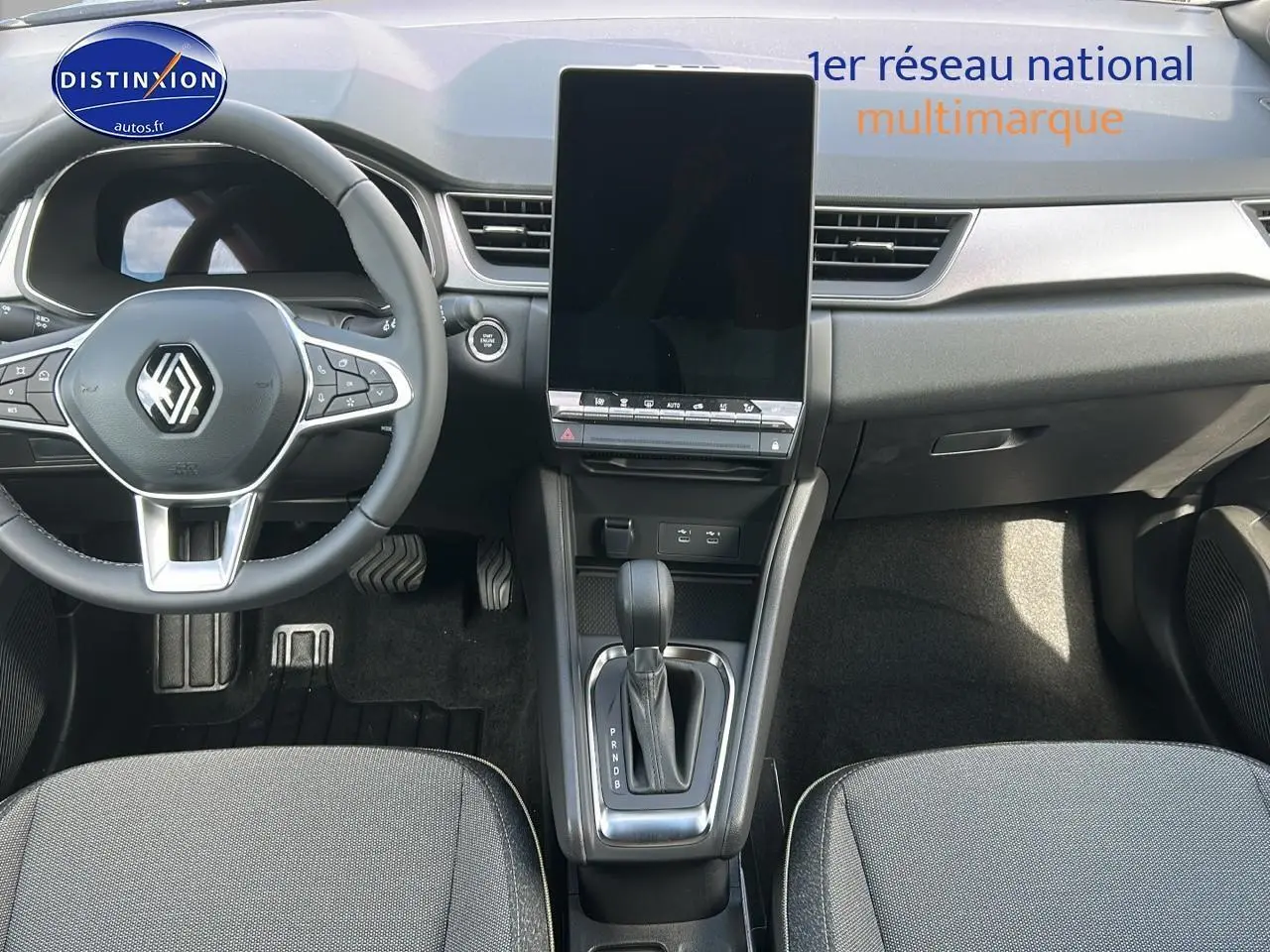 Intérieur avant du Renault Captur 2025, montrant le volant multifonction et l'écran tactile vertical central.