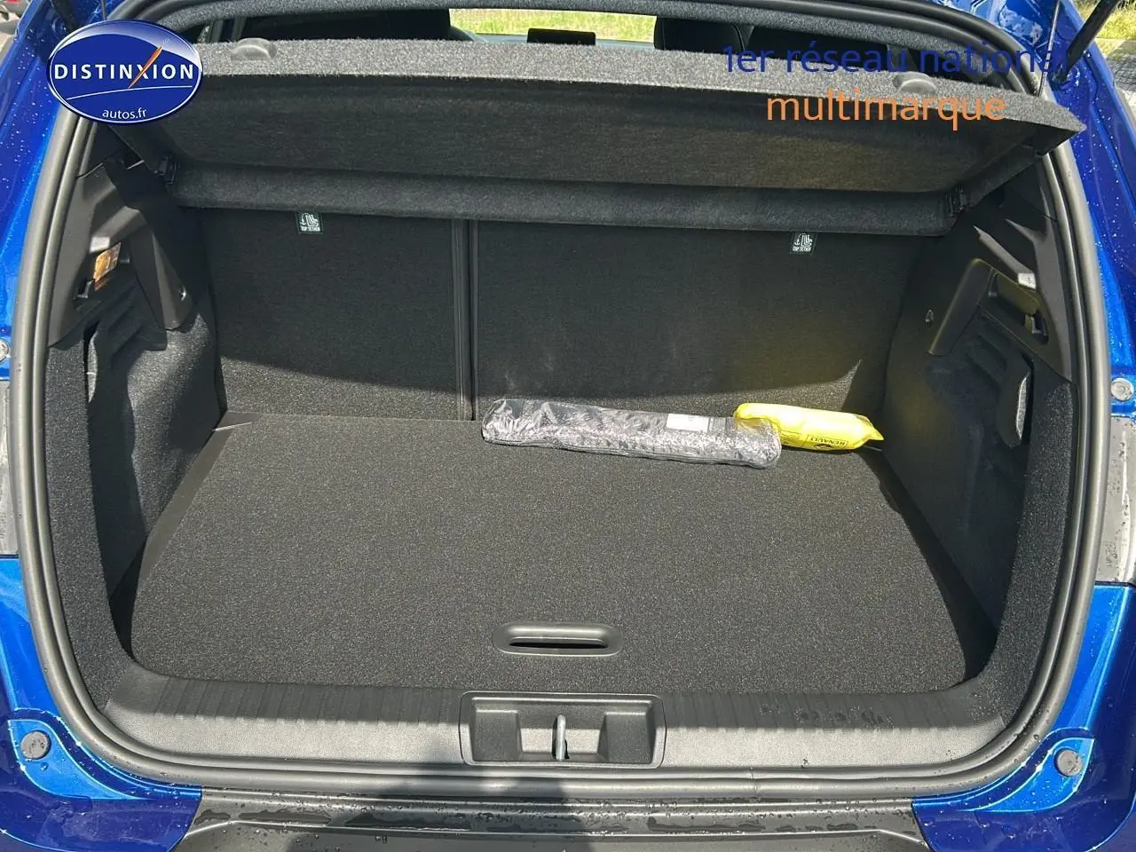 Coffre ouvert du Renault Captur bleu iron 2025, vue arrière montrant l'espace de chargement vide avec cache-bagages.