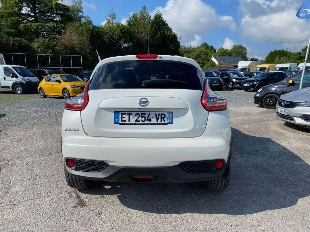 Vue arrière d'un Nissan Juke blanc 2017 avec feux arrière caractéristiques et lunette arrière surteintée.