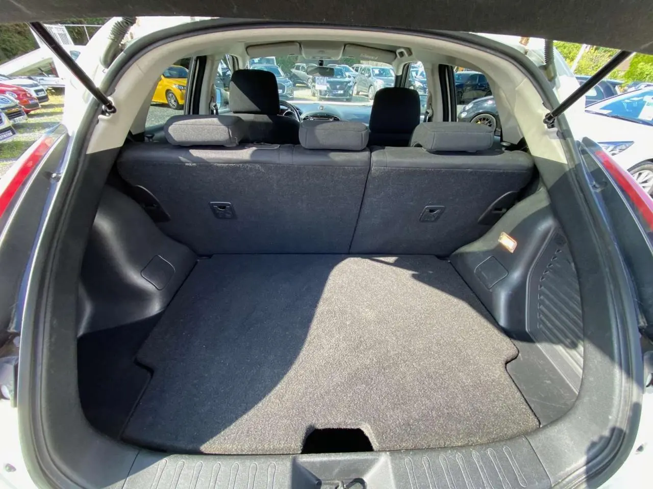 Coffre ouvert vu de l'arrière d'un Nissan Juke blanc 2017, montrant la banquette arrière et l'espace de chargement.