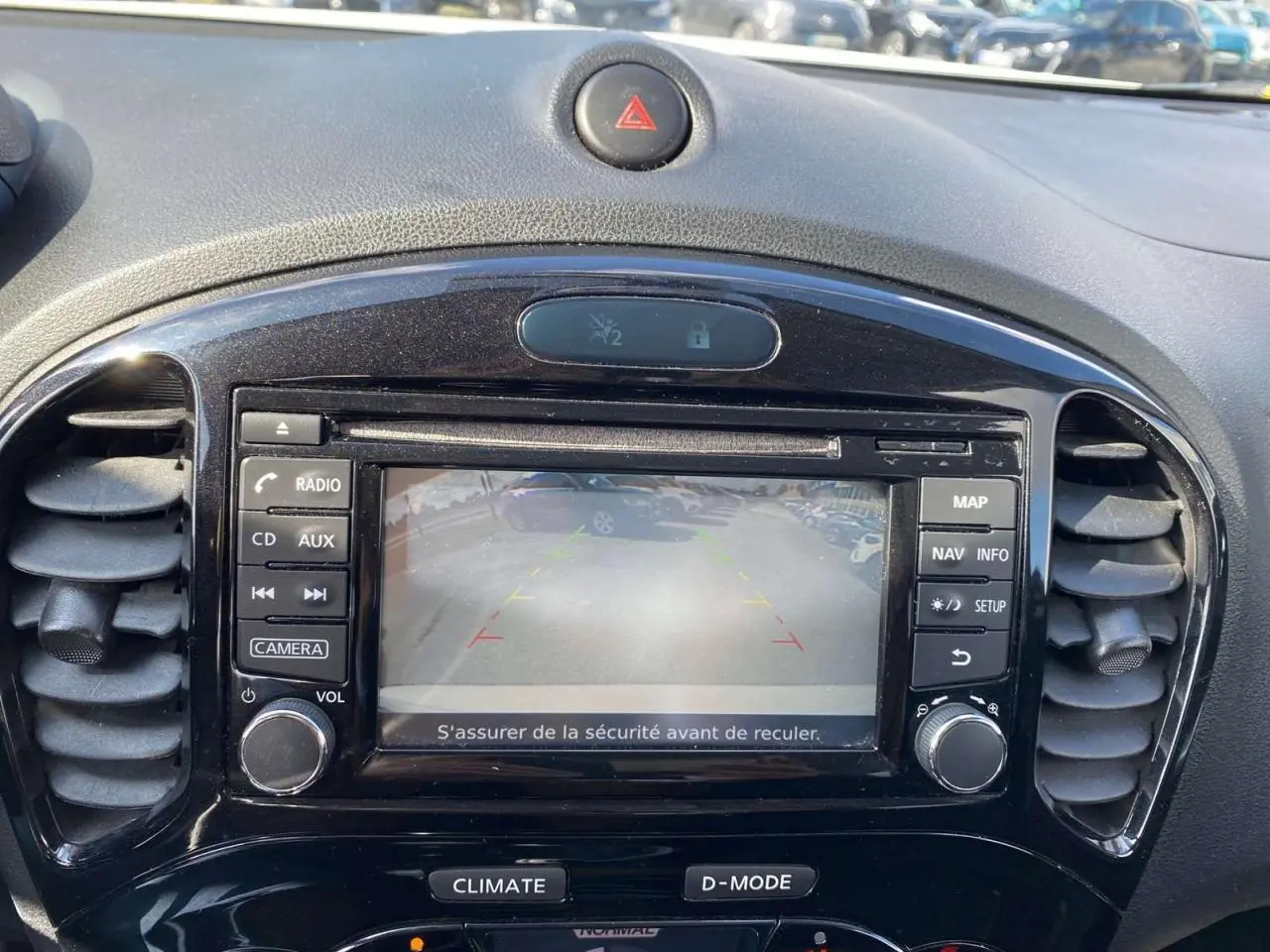 Vue rapprochée de l'écran central noir du Nissan Juke blanc 2017 affichant la caméra de recul et les commandes multimédia.