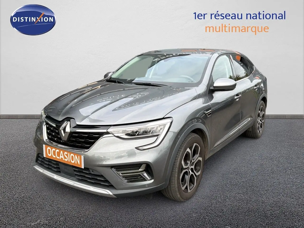 Renault Arkana gris 3/4 avant droit avec jantes bi-ton et calandre noire sur fond neutre showroom.