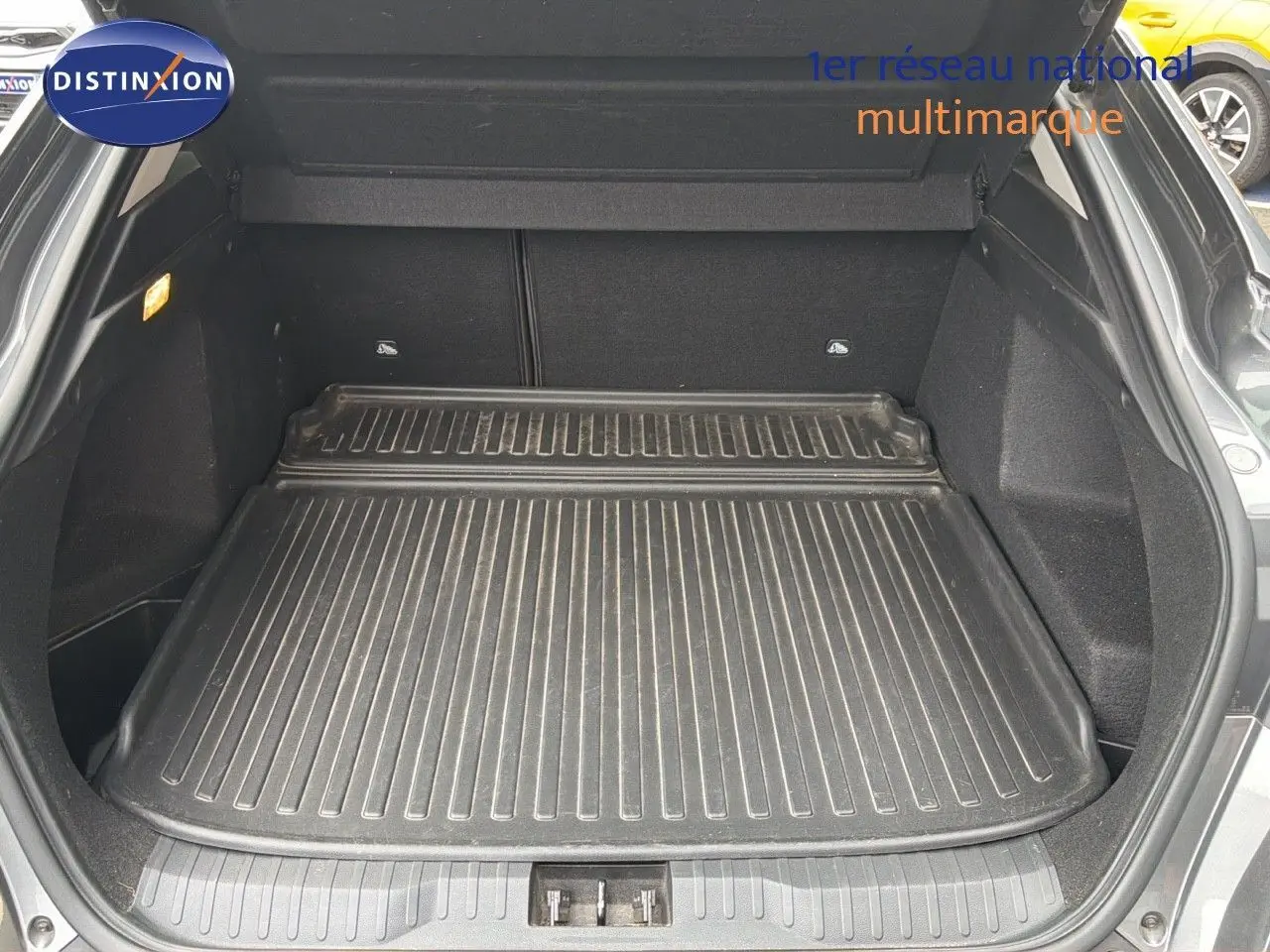 Coffre ouvert du Renault Arkana gris 2022, vue arrière montrant un tapis de protection noir dans le coffre spacieux.