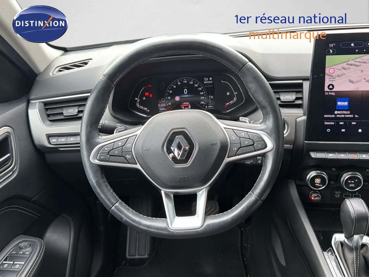 Vue intérieure centrée sur le volant cuir noir et le tableau de bord numérique du Renault Arkana gris 2022.