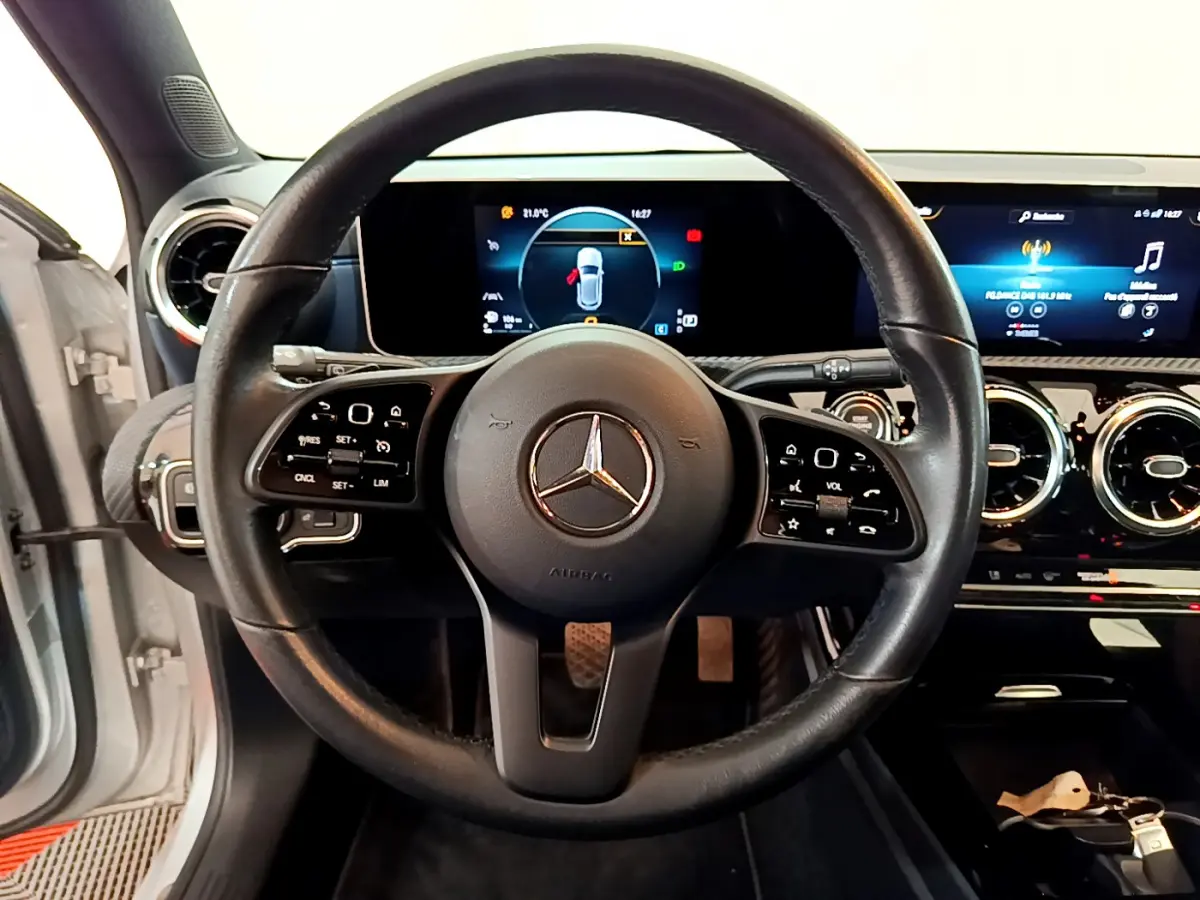 Vue intérieure centrée sur le volant cuir noir d’une Mercedes Classe A 180 d Business Line avec tableau de bord numérique.