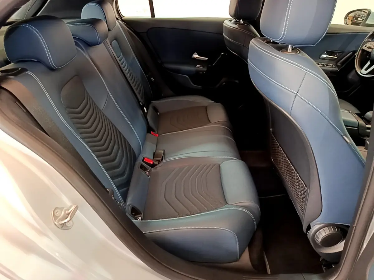 Vue intérieure côté arrière droit de la Mercedes Classe A 180 d Business Line 2020, sièges tissu bleu et noir avec surpiqûres blanches.