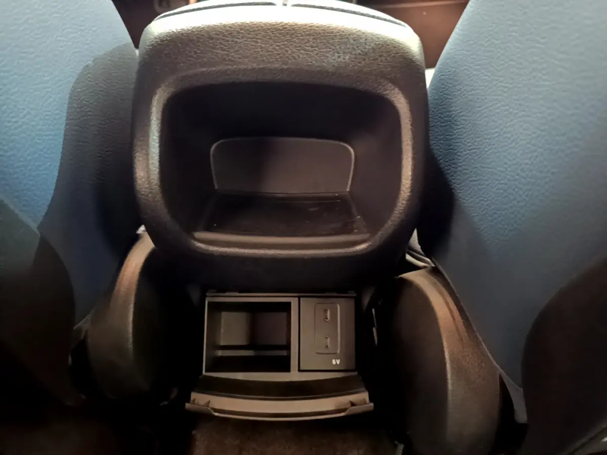 Vue rapprochée de la console arrière noire entre les sièges avant d’une Mercedes Classe A gris clair.