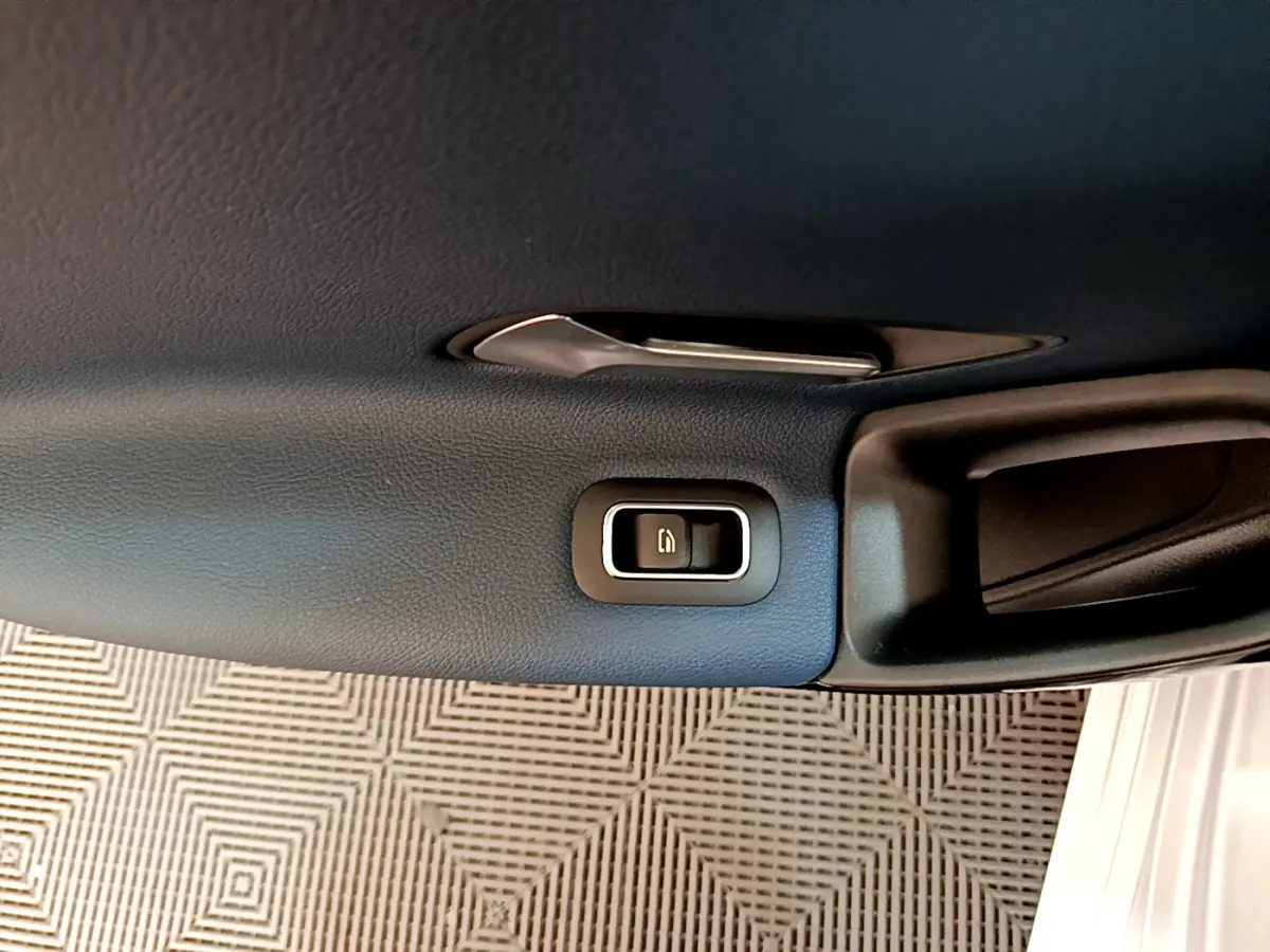 Détail de la poignée intérieure côté gauche avec bouton de verrouillage sur porte noire d’une Mercedes Classe A gris clair.