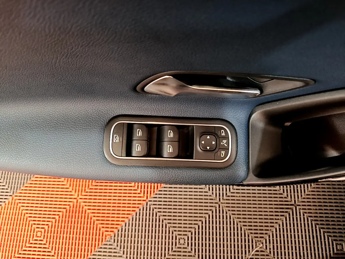 Gros plan sur la commande des vitres et rétroviseurs côté conducteur d'une Mercedes Classe A 180 d Business Line 2020, intérieur bleu.
